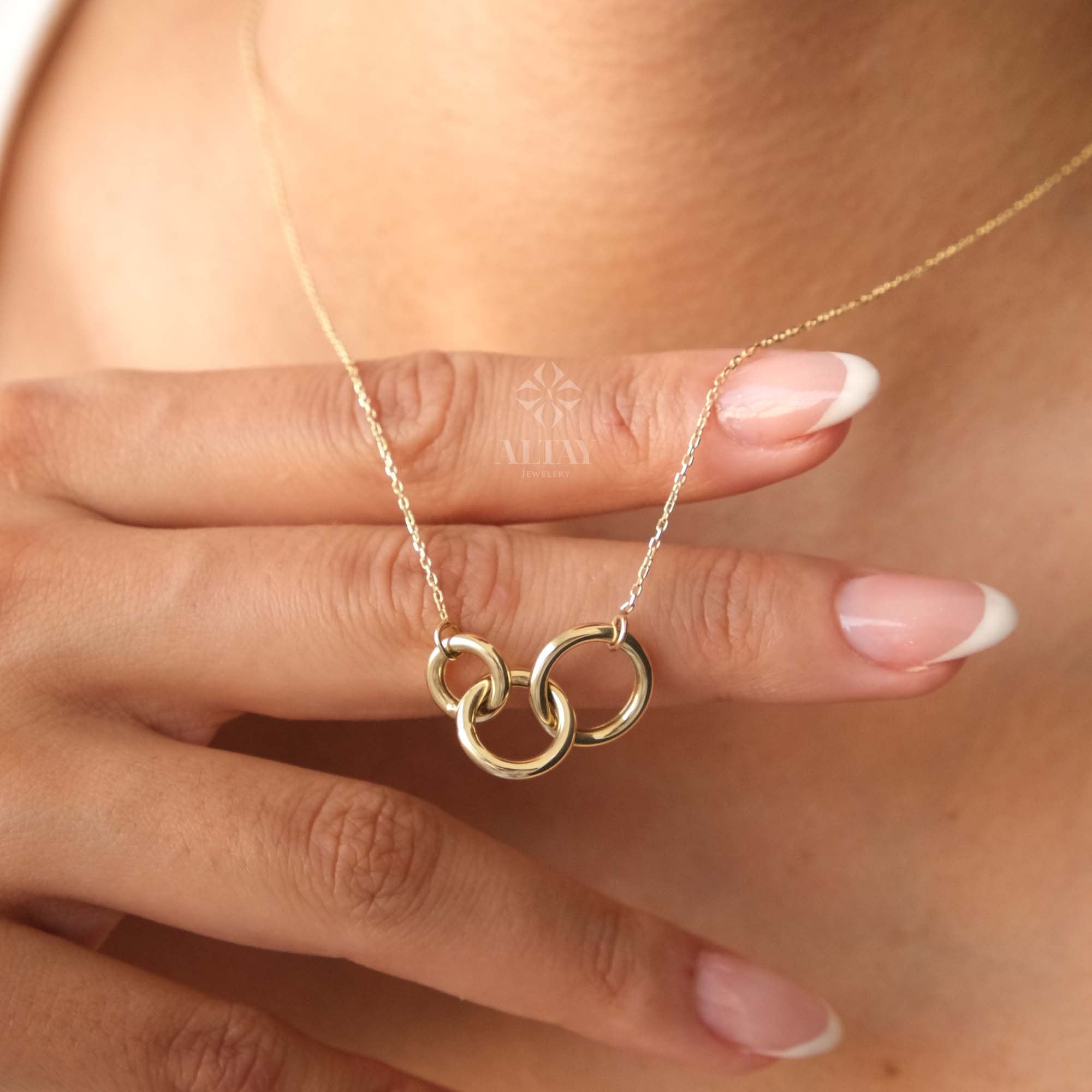 May include: A gold necklace with a pendant featuring three interlocking circles.