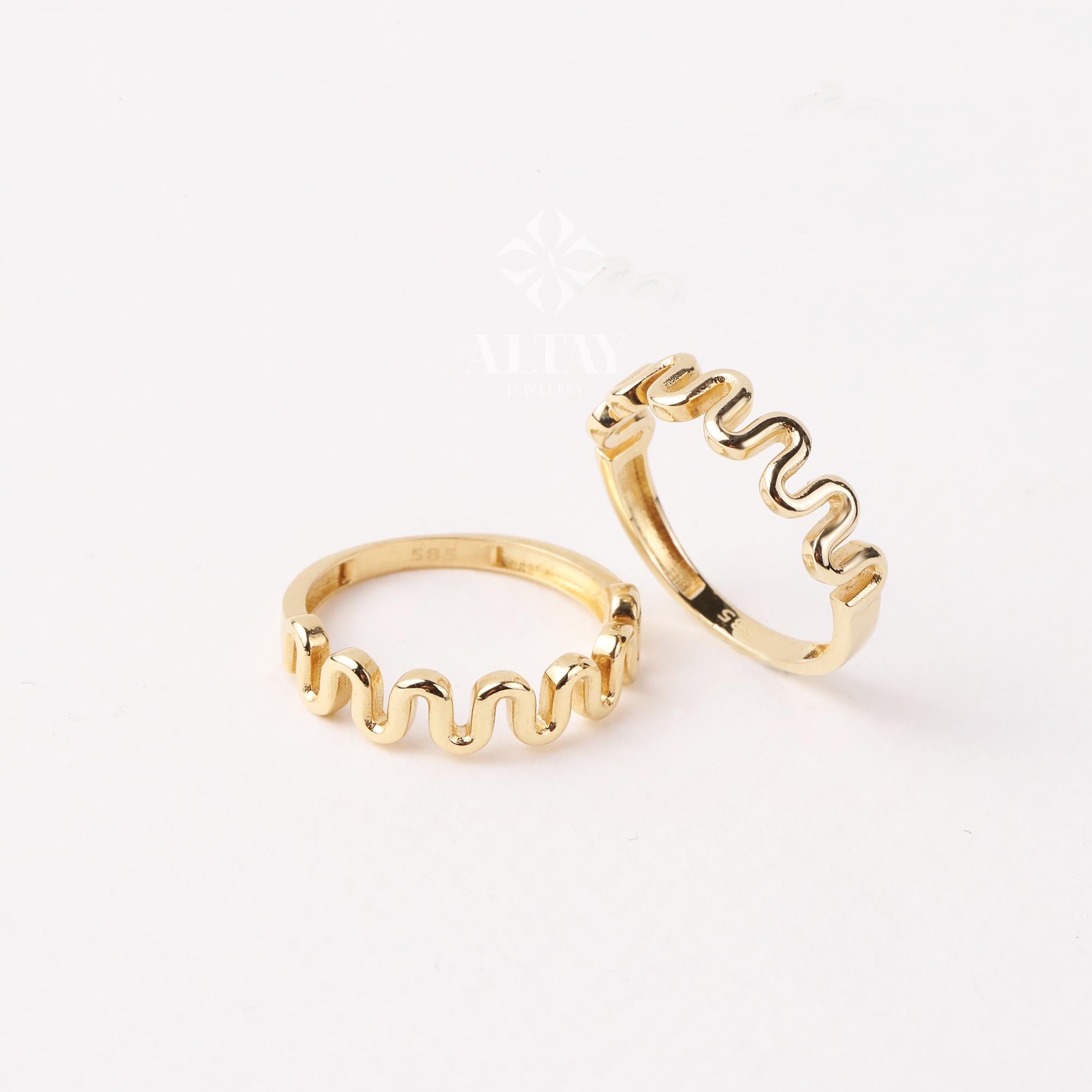 May include: Two gold-toned rings with a wavy, undulating design. The rings are stacked on top of each other.