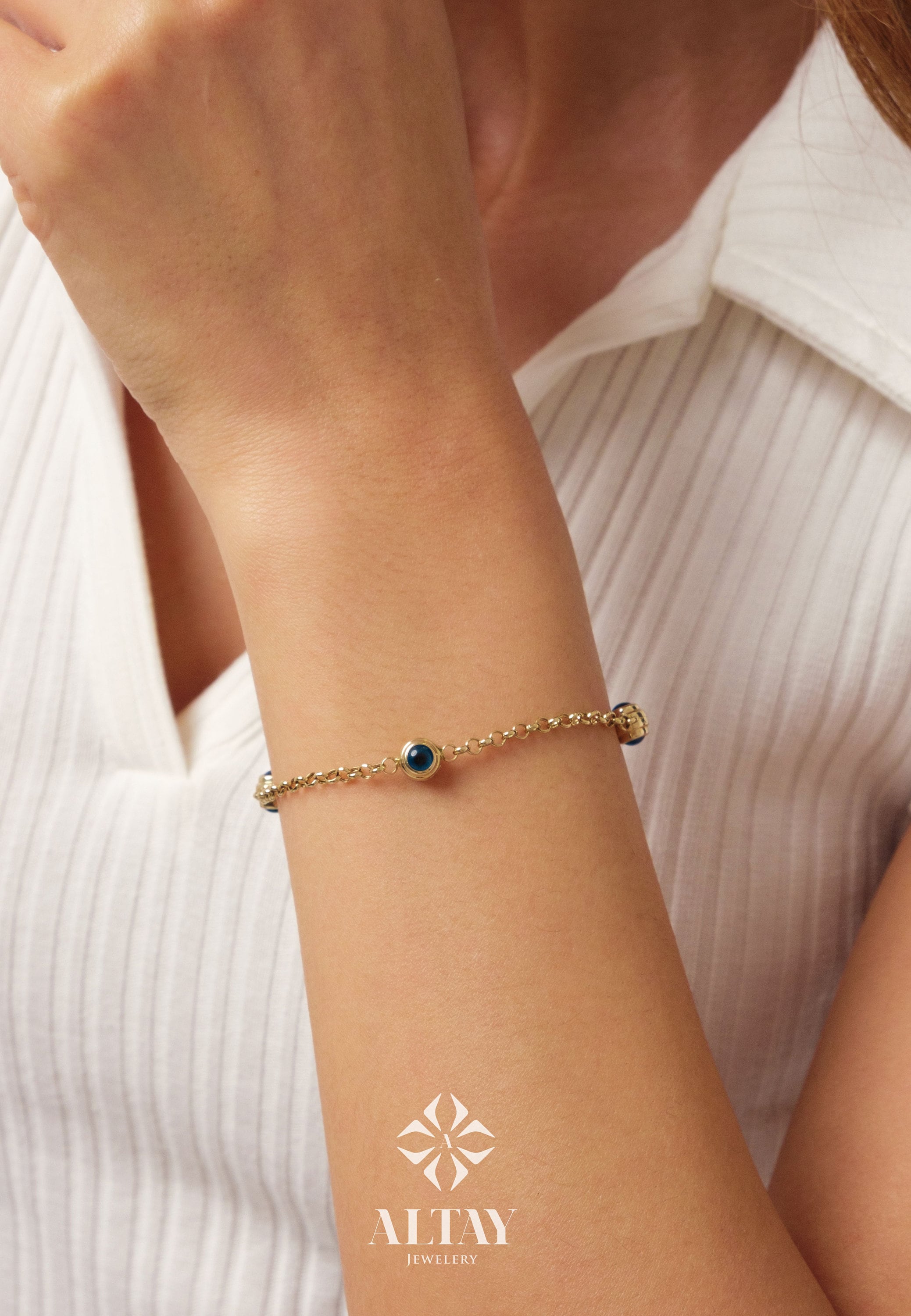 May include: A gold chain bracelet with blue evil eye charms. The bracelet is on a person's wrist.