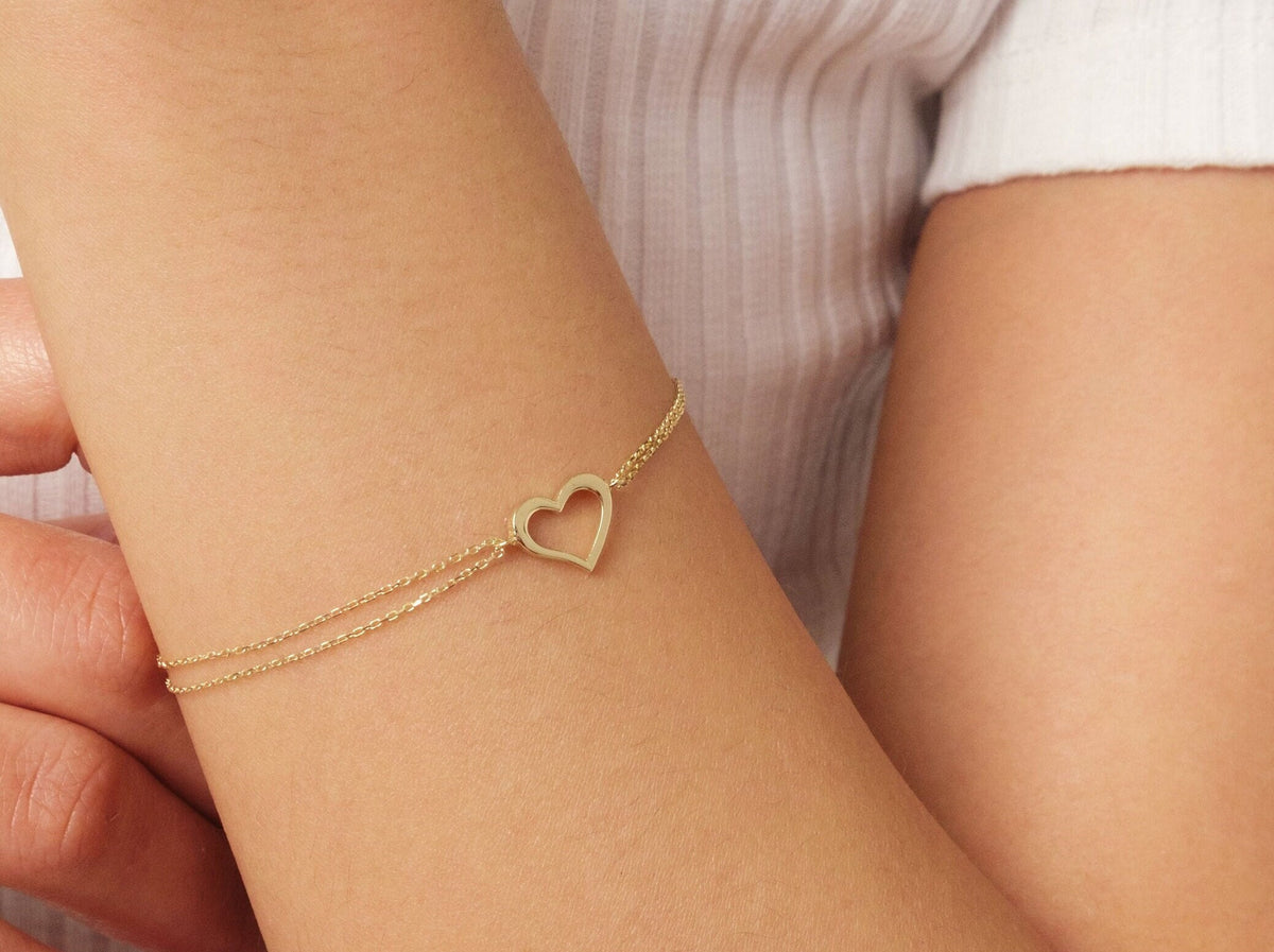 May include: A gold heart-shaped charm bracelet with a delicate chain.