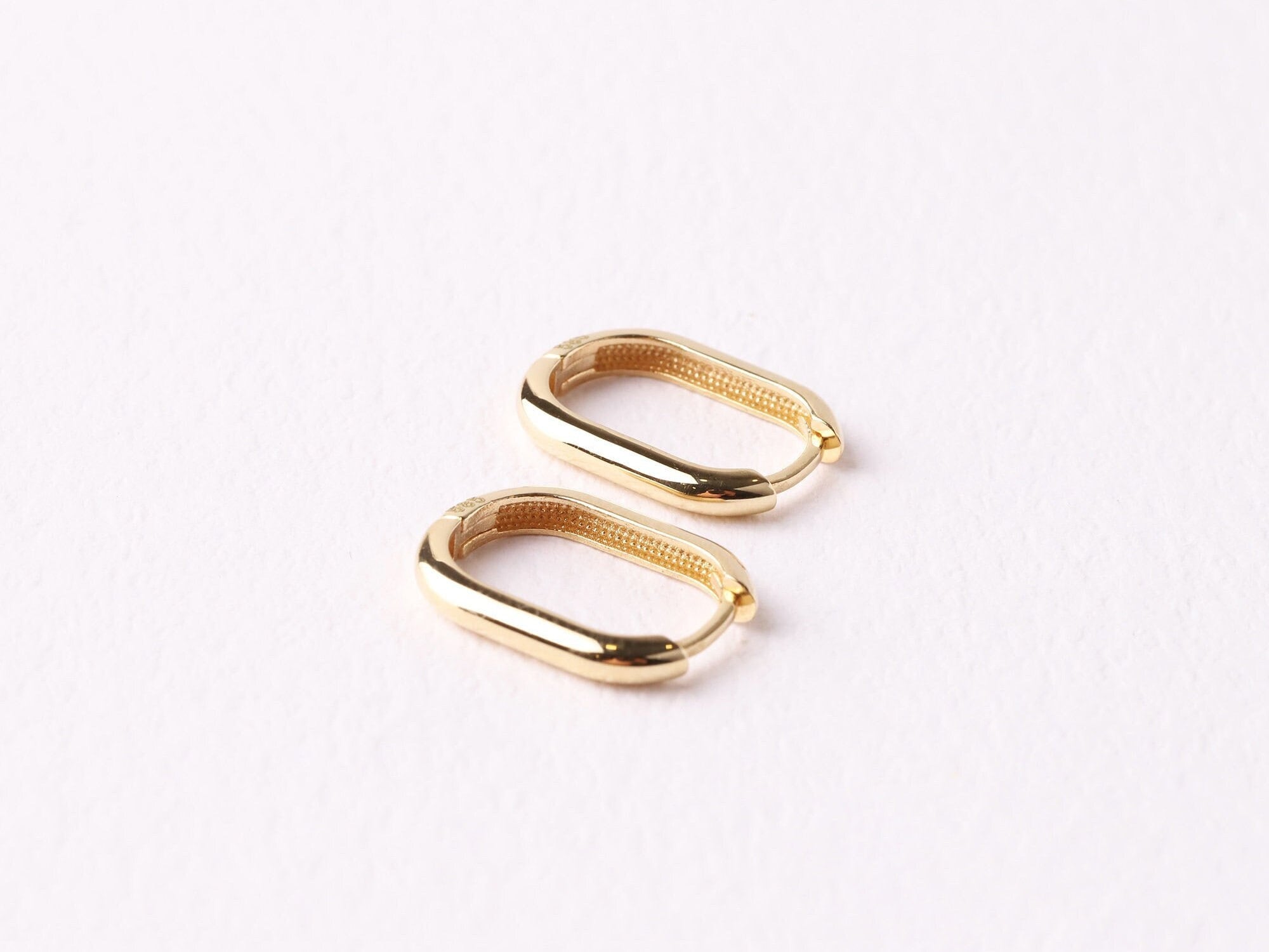 May include: A pair of gold oval hoop earrings. The earrings are simple and elegant.