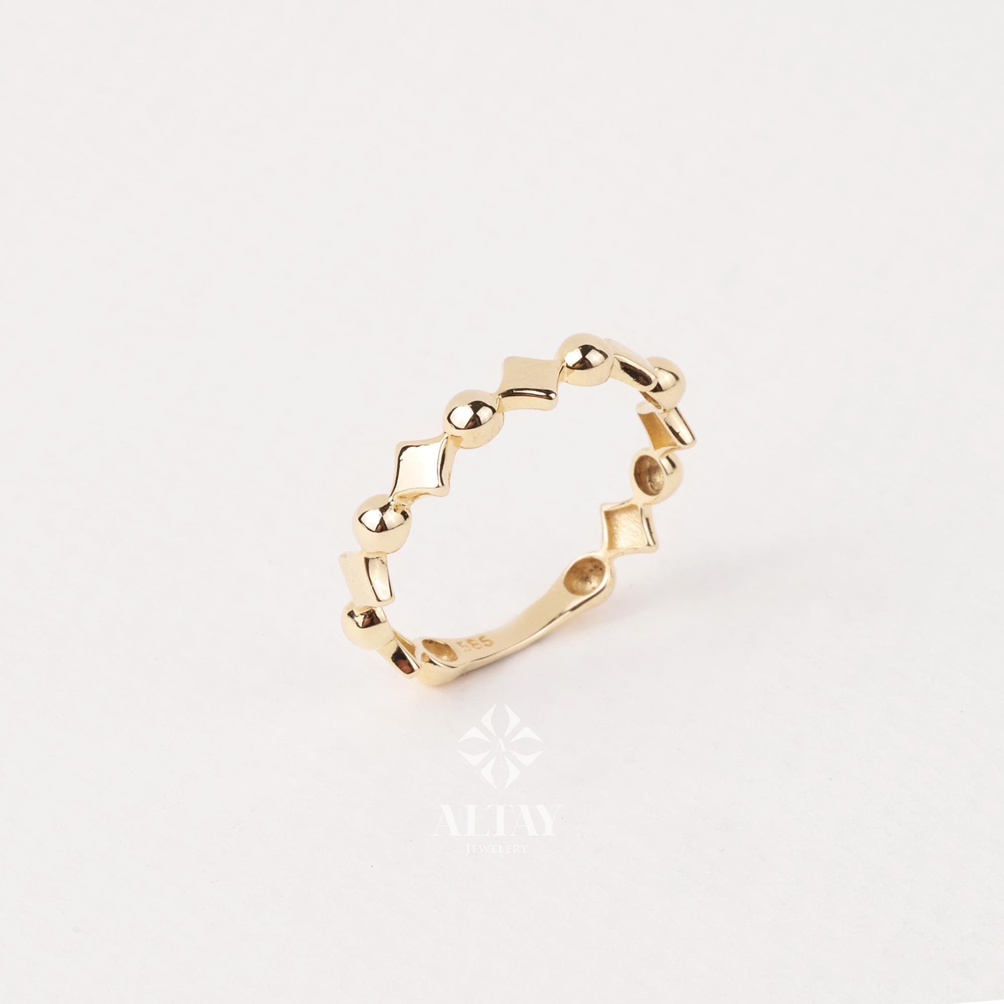 May include: A gold ring with a repeating pattern of diamond and circular shapes. The ring is set against a white background, highlighting its intricate design and polished finish. The ring is a delicate piece of jewelry.